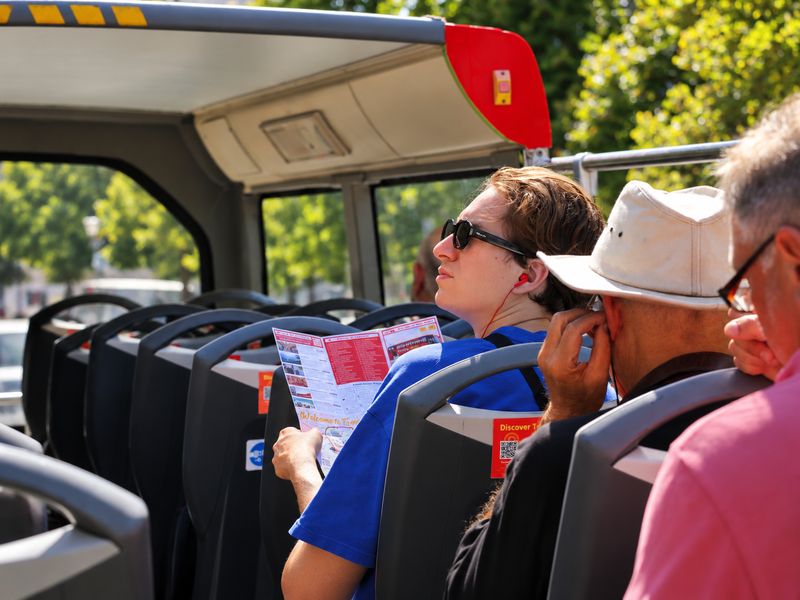 Passengers using the multilingual audio guide on the HOBUS hop-on hop-off bus in Tirana