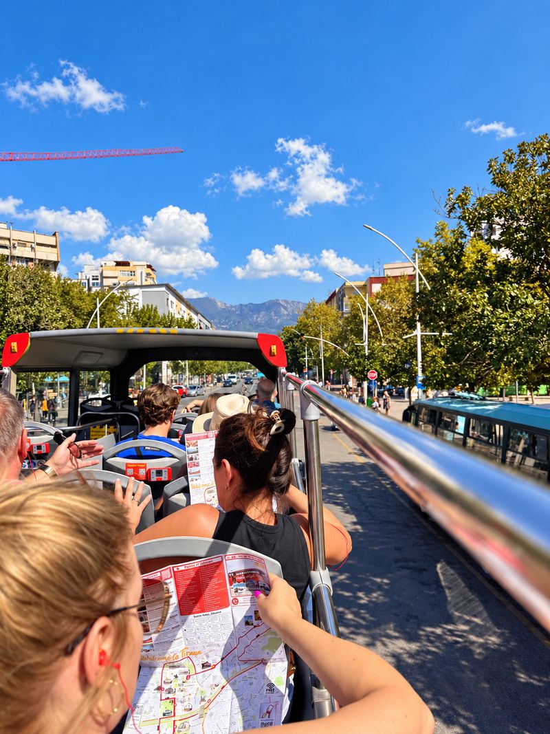 Visitor reading a city map on the open-top HOBUS sightseeing bus in Tirana